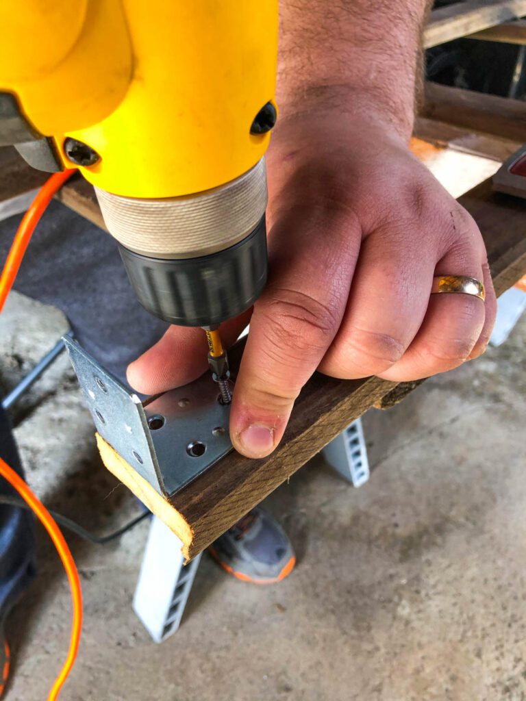 man uses drill to put together a do-it-yourself garden trellis