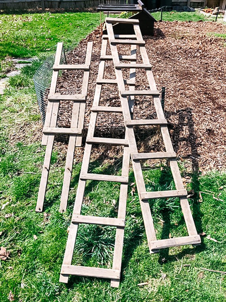 stacks of wooden ladders leaning on a metal fence