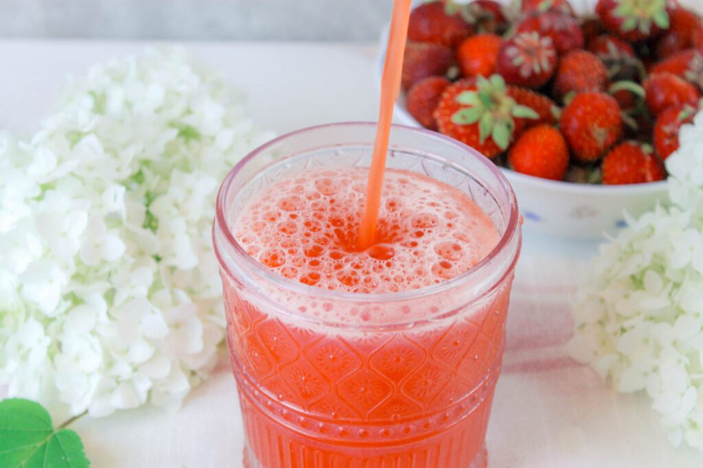 man pours strawberry lemonade into a pink cup