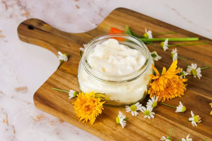 ball mason jar filled with body butter sitting on a marble countertop
