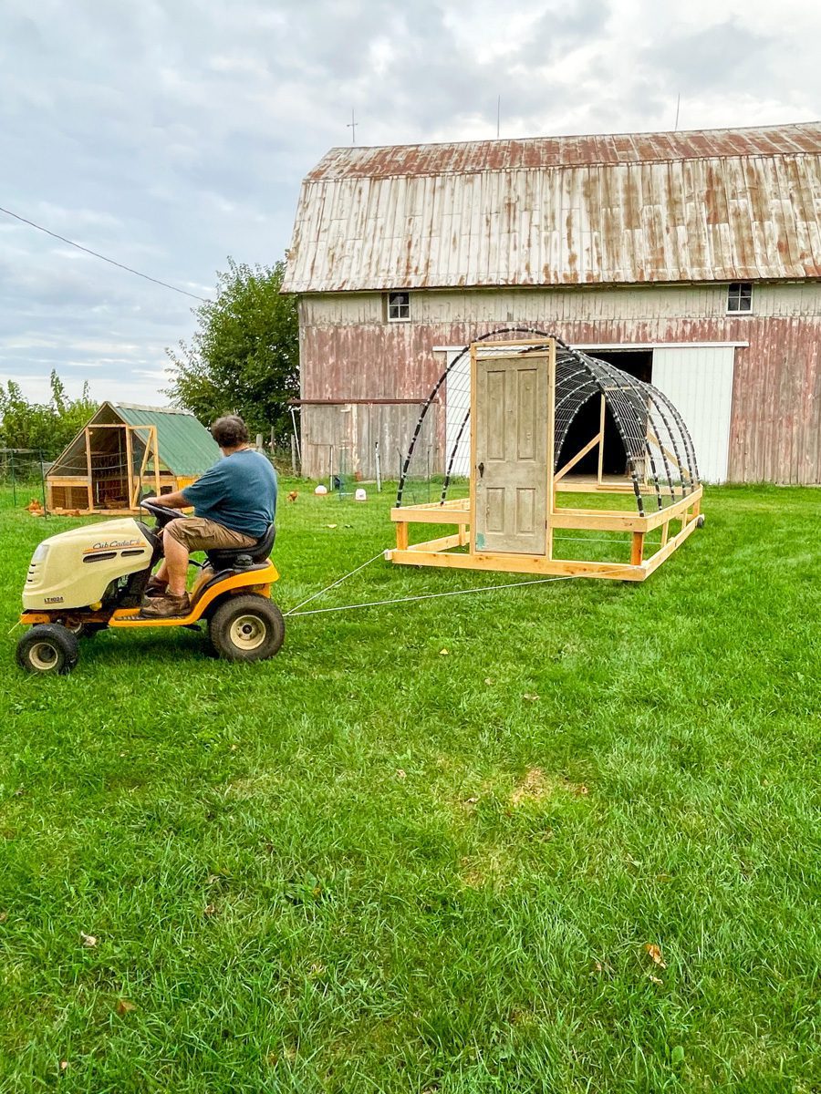 man on a tractor pulling a moveable greenhouse