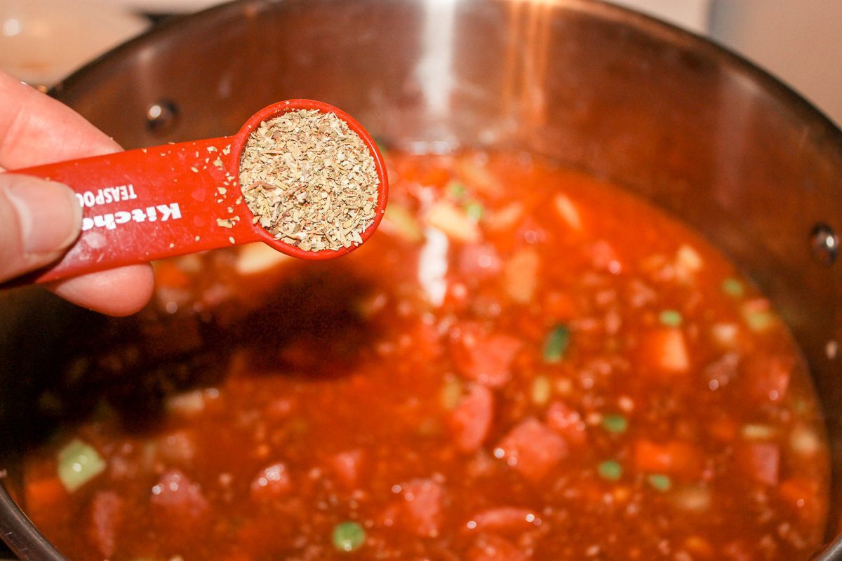 adding a teaspoon of Italian seasoning into a pot of soup