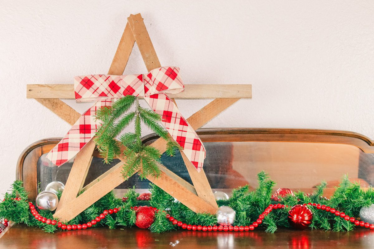 diy wooden star sits on a dressed surrounded by Christmas decorations