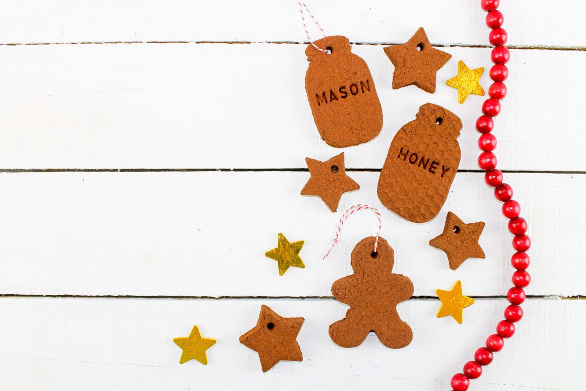 a variety of cutout cinnamon spice ornaments sit beside a Christmas star and a set of red holiday beads