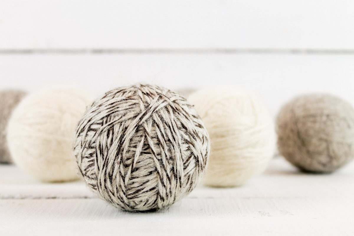 5 wool dryer balls sitting on a white wooden background