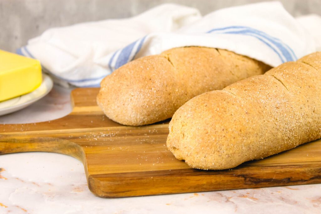 two freshly baked loaves of bread sit on a kitchen countertop cooling
