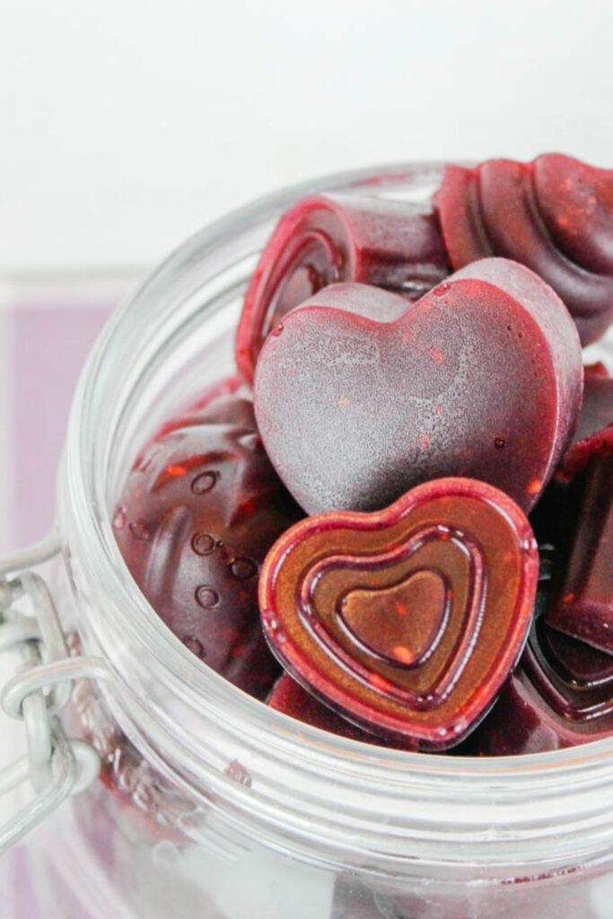 close up of heart shaped fruit gummies inside a glass jar