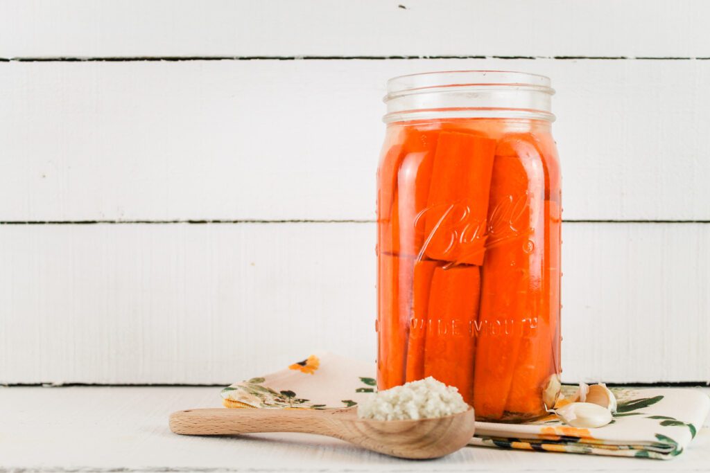 mason jar filled with pickled carrots sitting on a wooden board