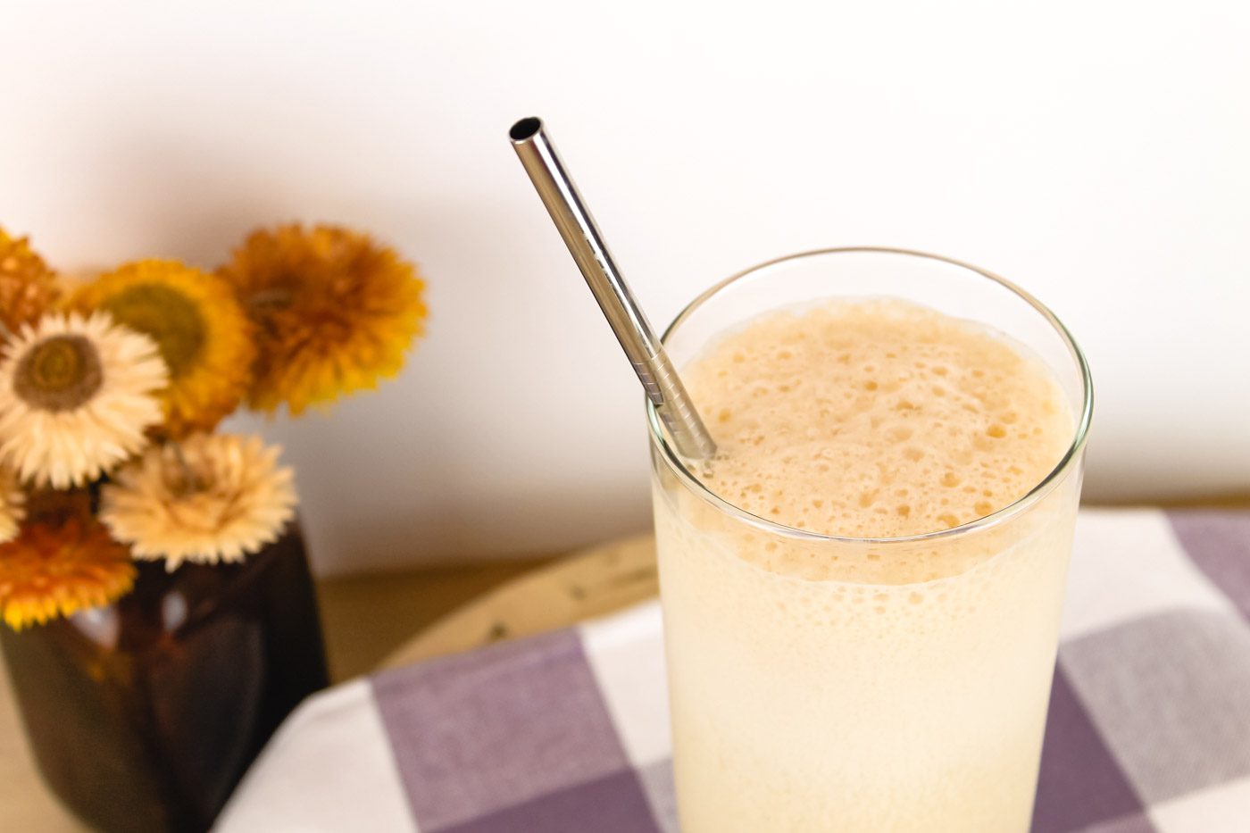 clear glass of kefir frappe sitting beside a vase of flowers