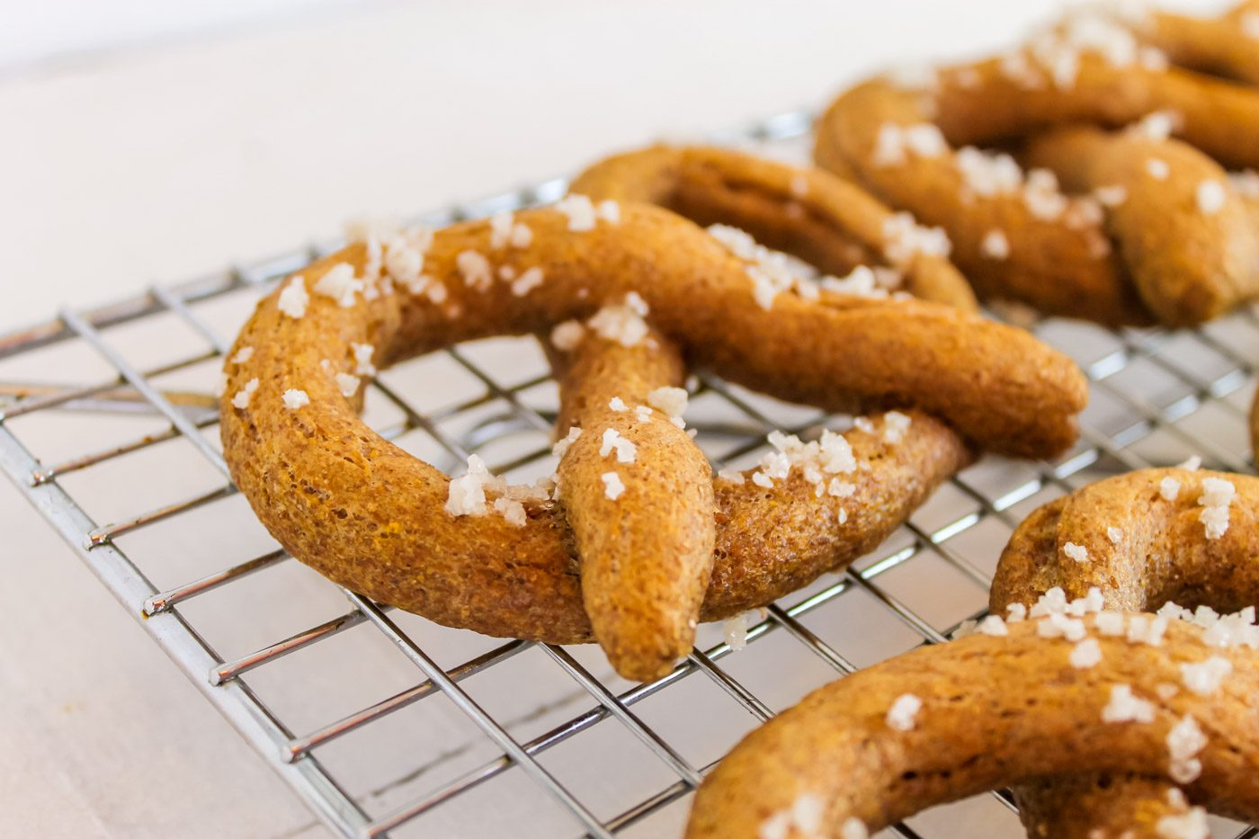 homemade soft pretzels covered in sea salt sitting on a baking rack