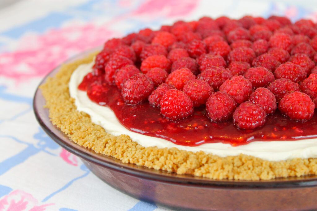 side view of a healthy raspberry pie topped with fresh berries