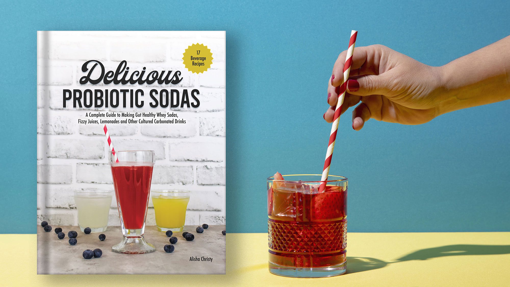 probiotic soda book sits next to a glass of strawberry soda with a red striped straw