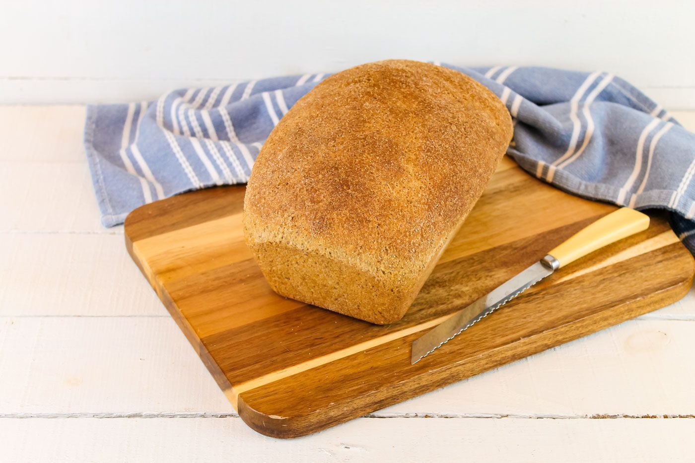 fresh loaf of sourdough bread sitting on top of a wooden cutting board next to a bread knife
