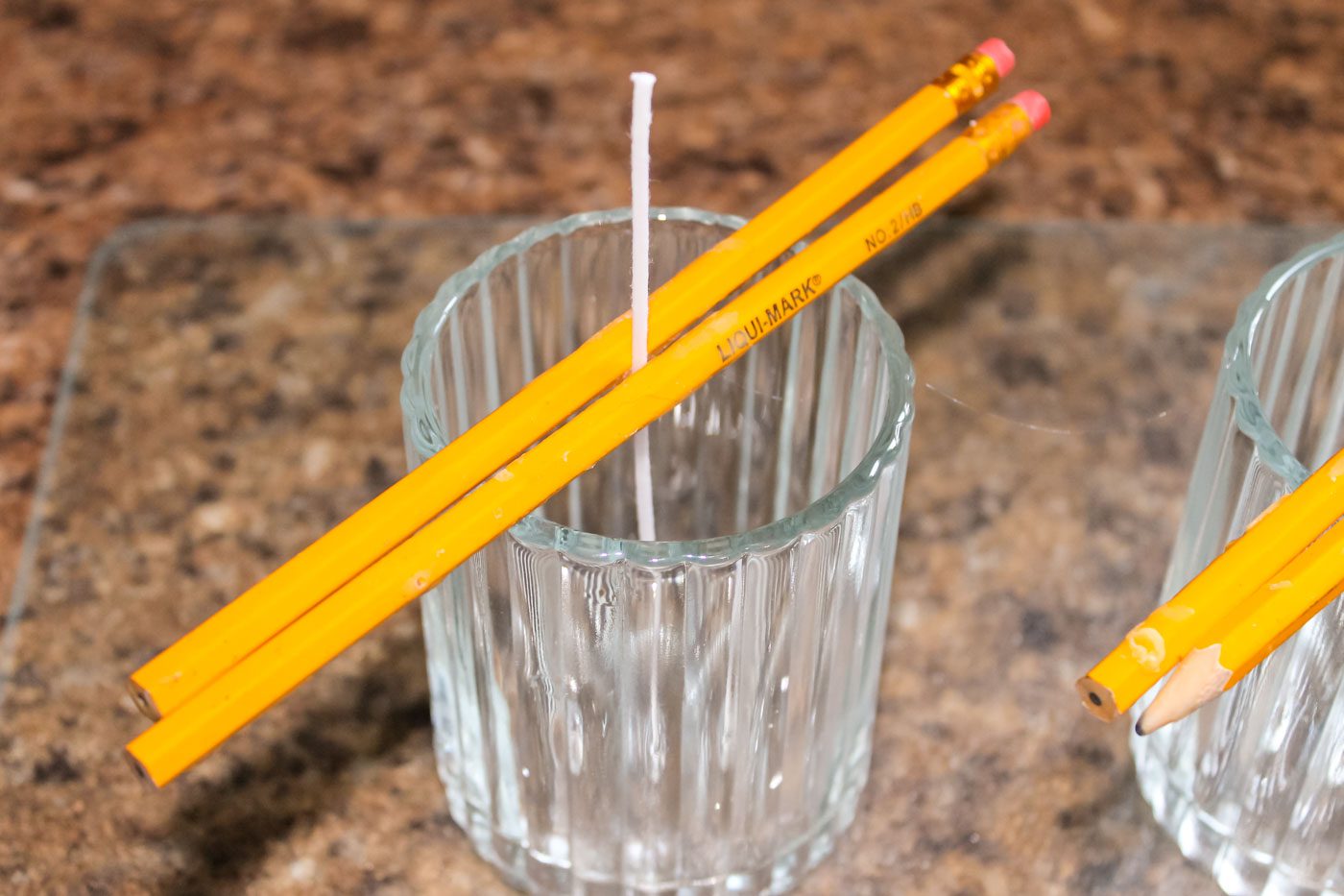 candle wick sits in a jar held by two pencils