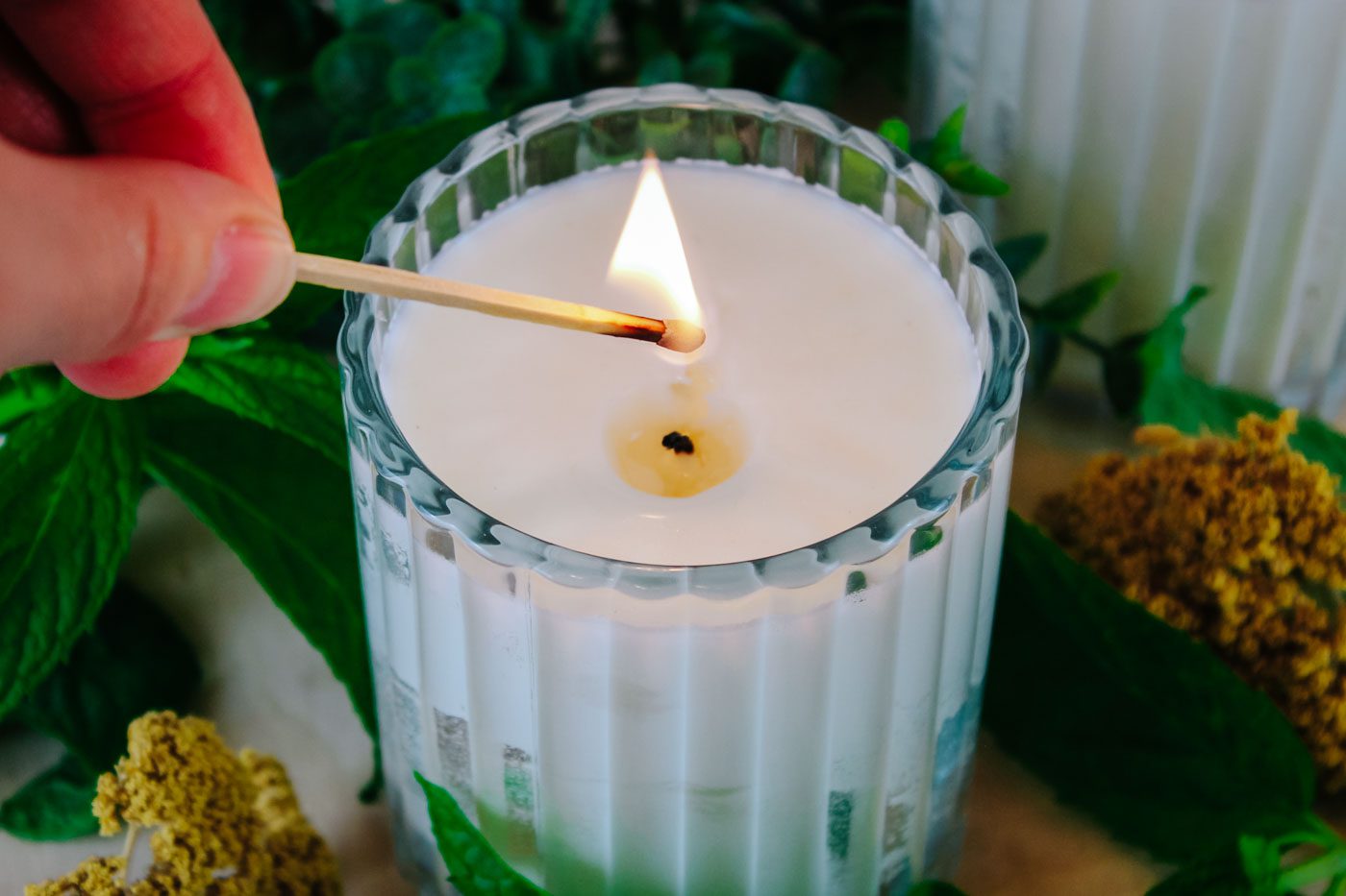 hand holds a match to light a candle