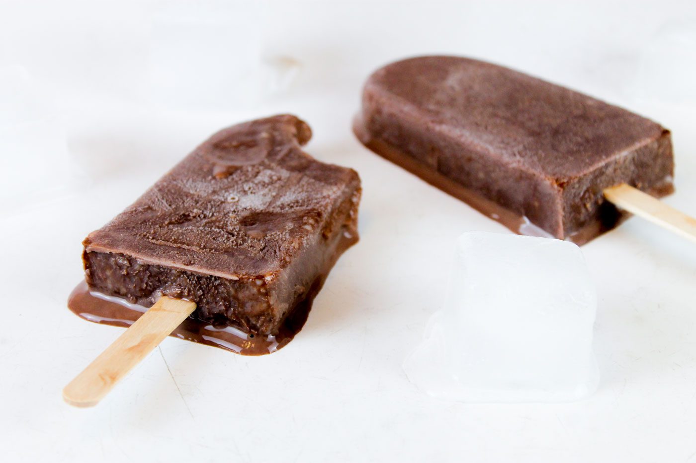 2 chocolate kefir popsicles sitting on a countertop melting