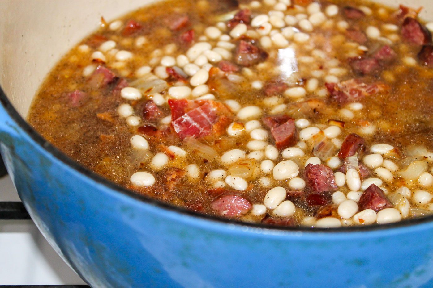 dutch oven sits on stovetop with simmering baked beans
