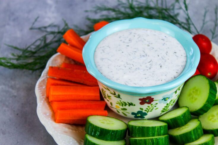 sliced vegetable plate with bowl of dip in center of plate