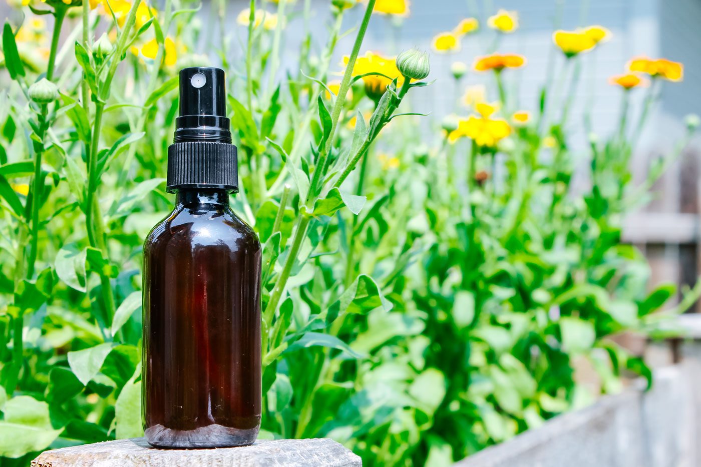 glass amber spray bottle with fresh flowers in the background
