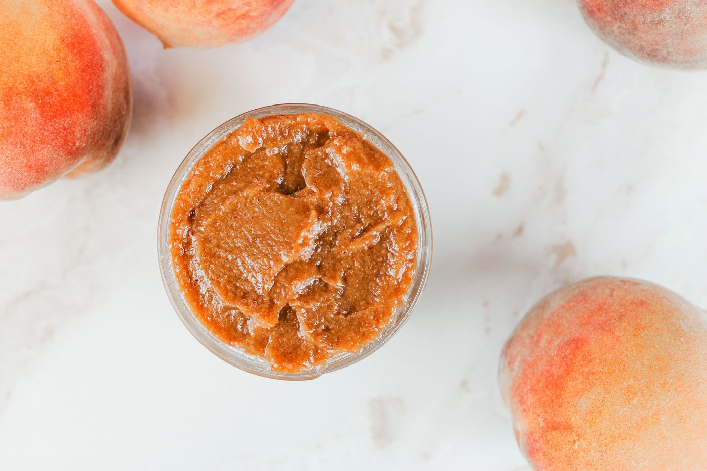 top view photograph of glass jar full of peach butter