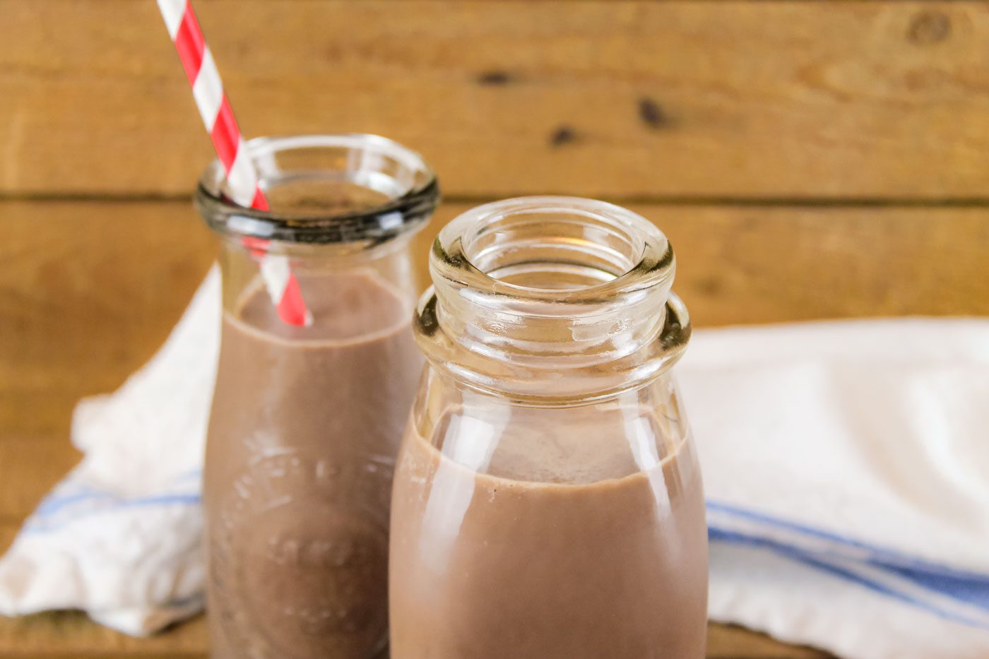 2 bottles of chocolate milk. one bottle has a red and white striped straw coming out of the top.