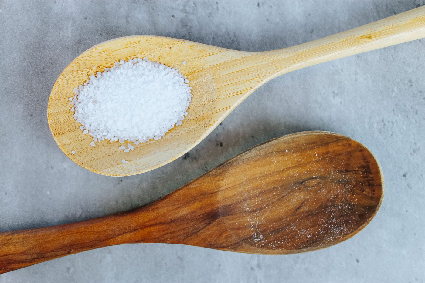 two wooden spoons with one filled with coarse white salt
