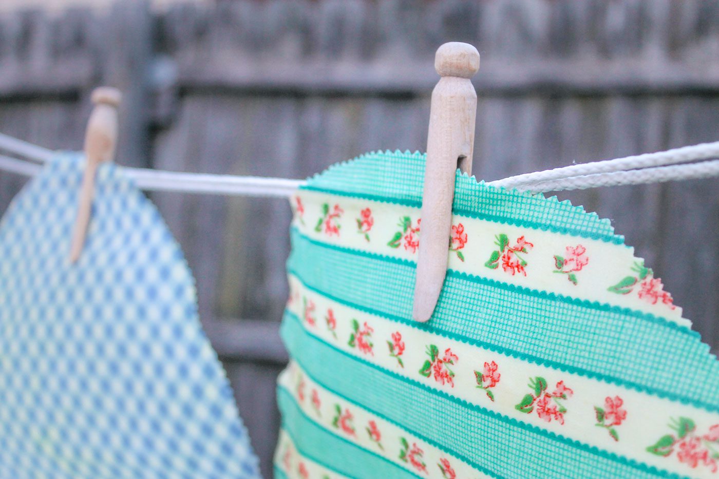 two pieces of homemade beeswax wraps hang on a clothesline 