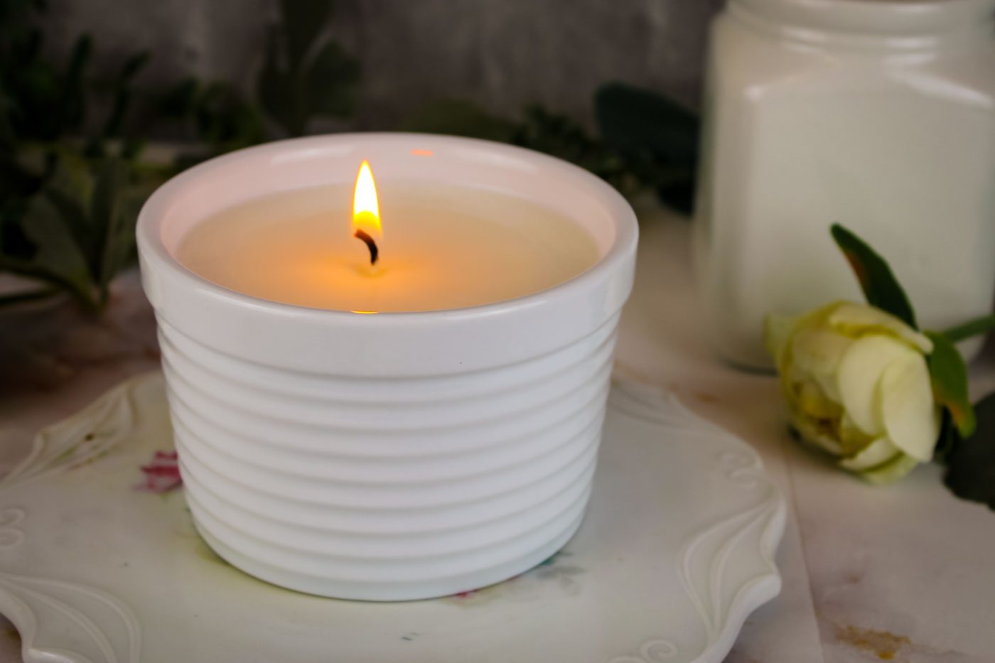 candle burning inside a white striped white glass container