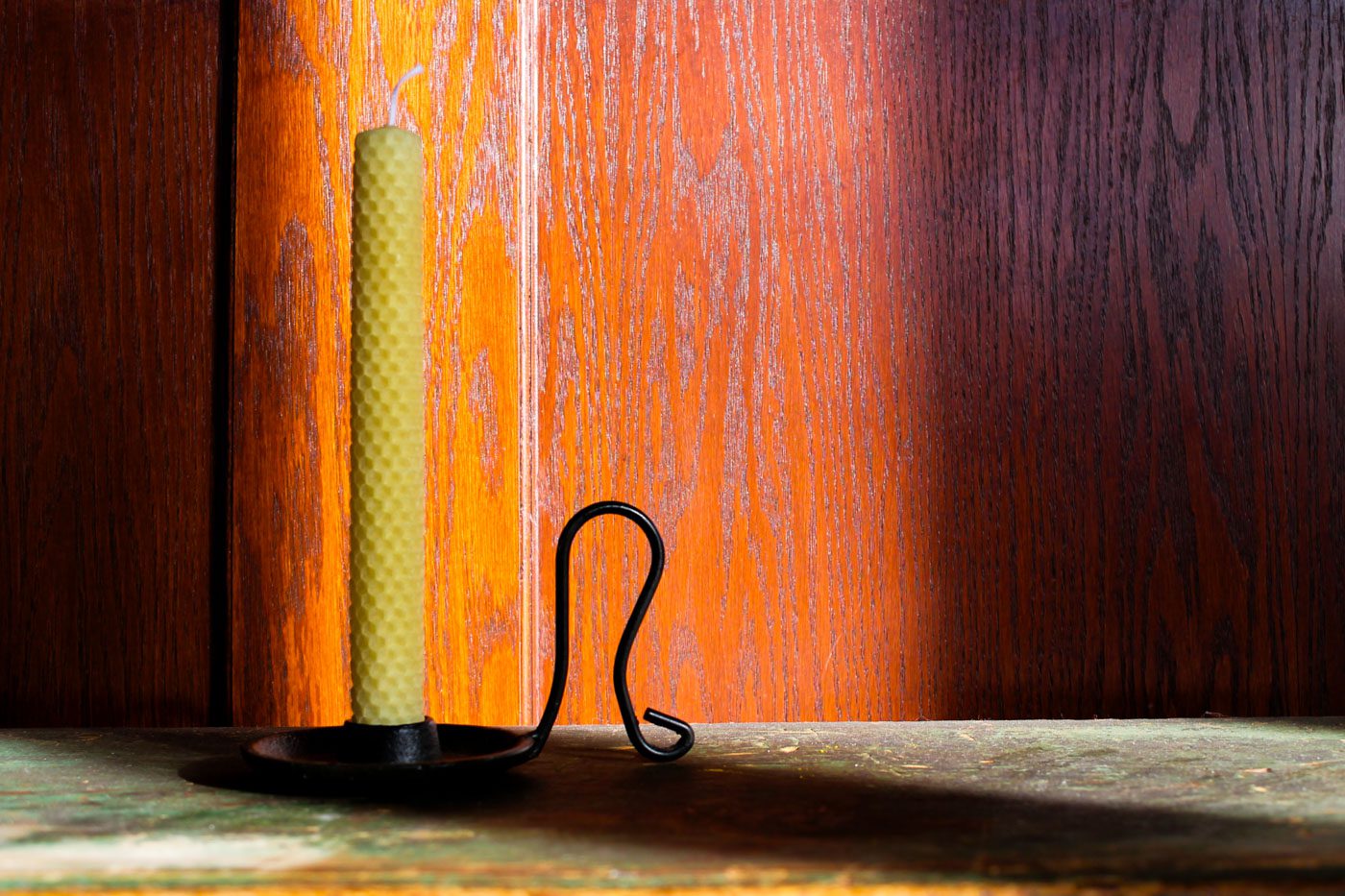 light shines in through a window onto a yellow rolled beeswax candle