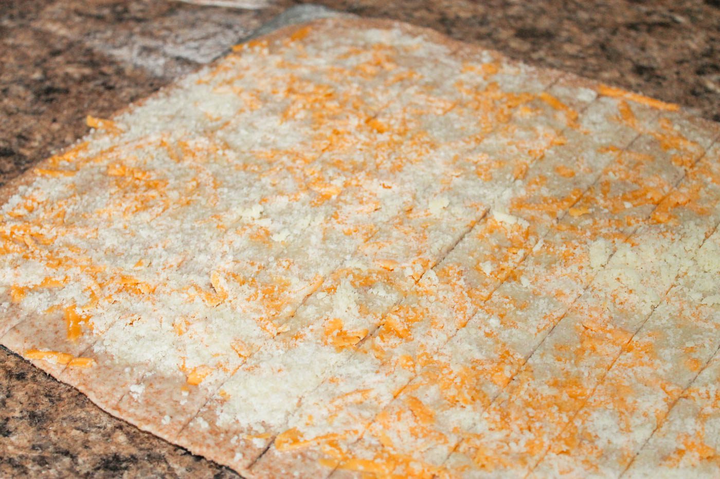 rolling out dough with cheese sprinkled on top