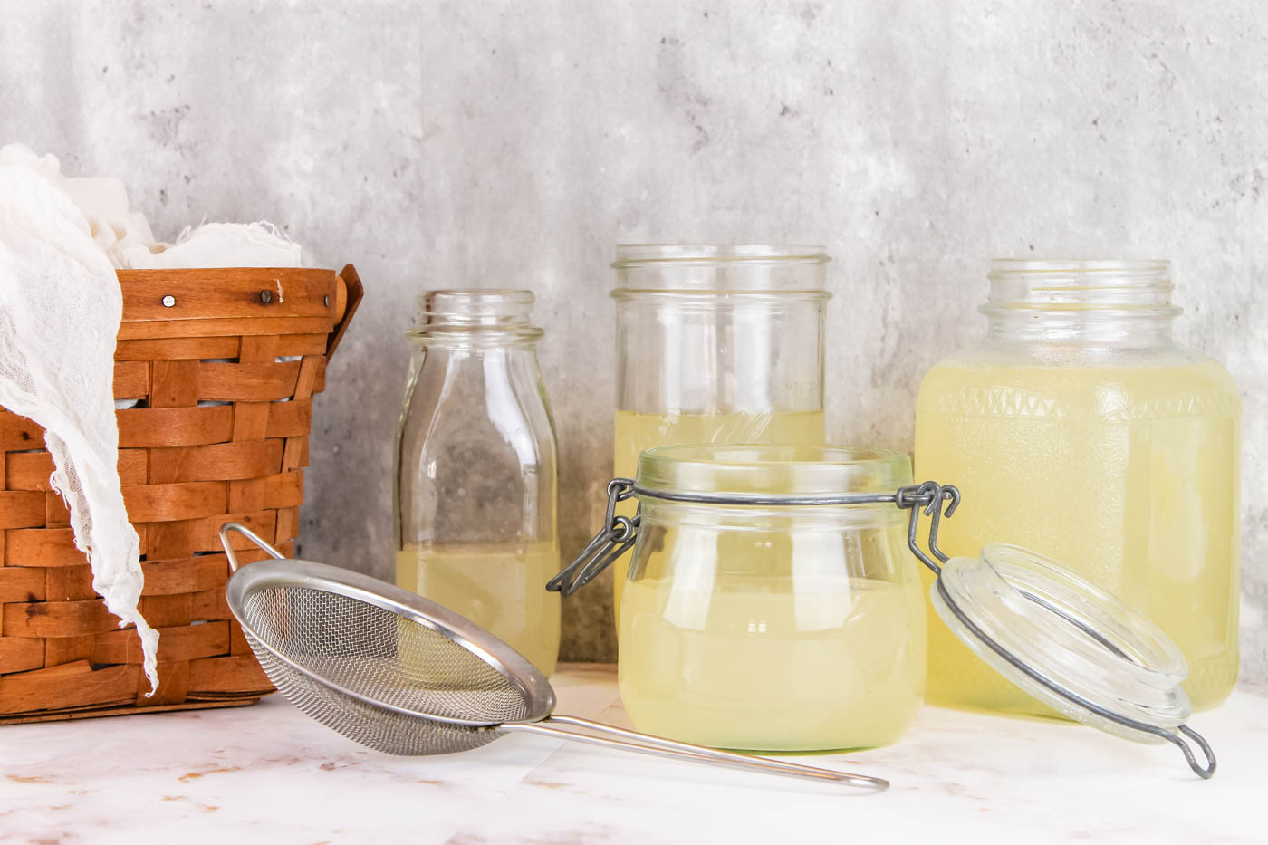 multiple glass jars filled with whey sitting on a white countertop