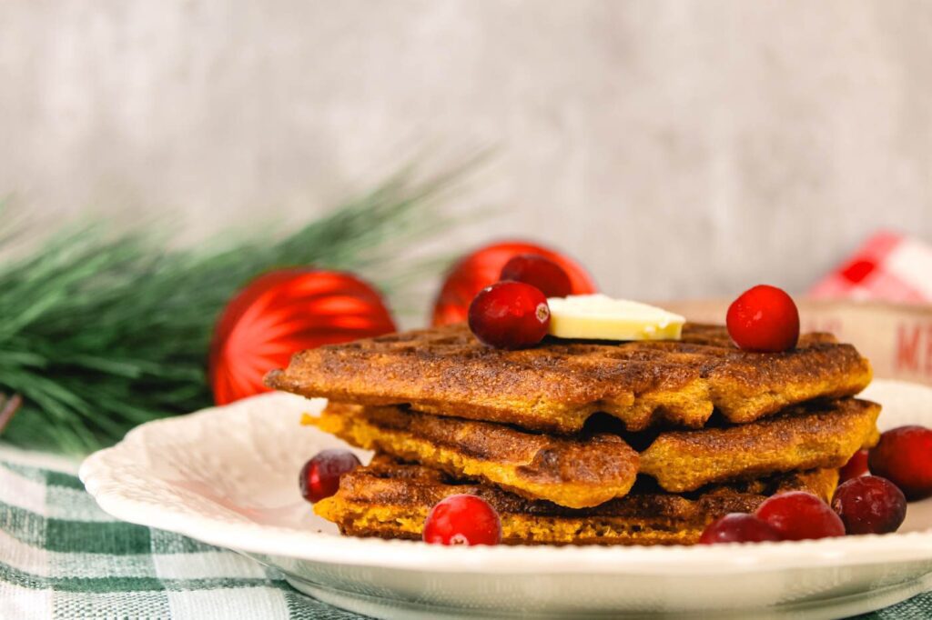 gingerbread waffles covered in butter sitting on a countertop with Christmas decorations