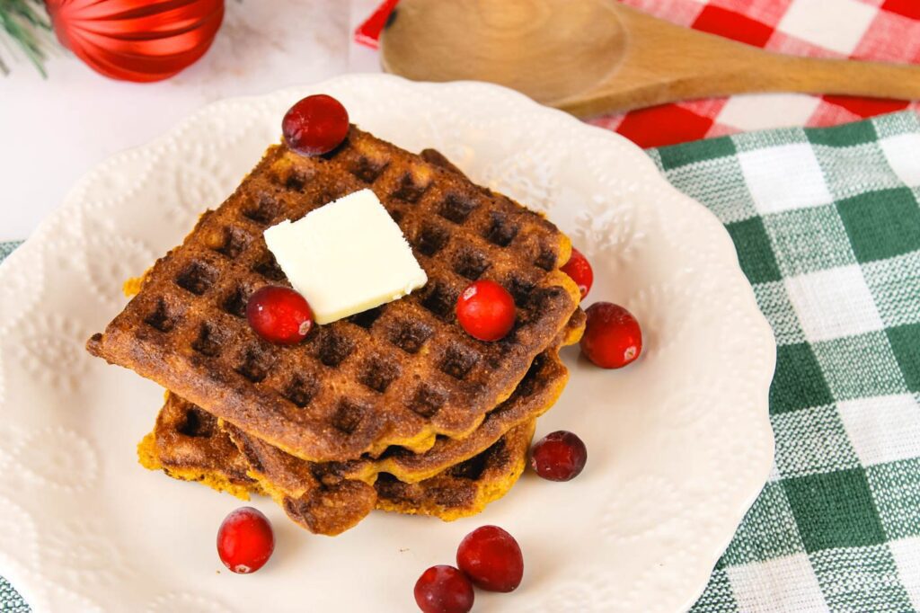 stack of waffles covered in butter and fresh cranberries