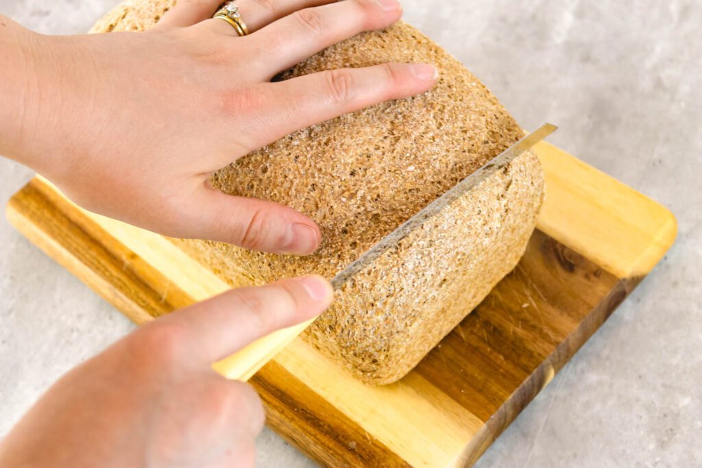 a woman's hand cutting slices of bread