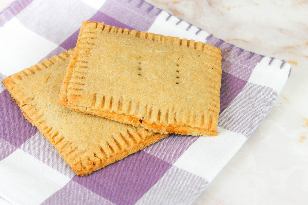 a whole grain pop tart rests on the top of another pastry while sitting on a checkered kitchen towel