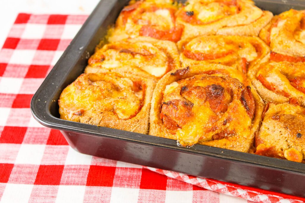 a pan of pepperoni pizza rolls sitting on a red and white checkered towel