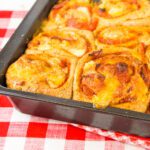 a pan of pepperoni pizza rolls sitting on a red and white checkered towel