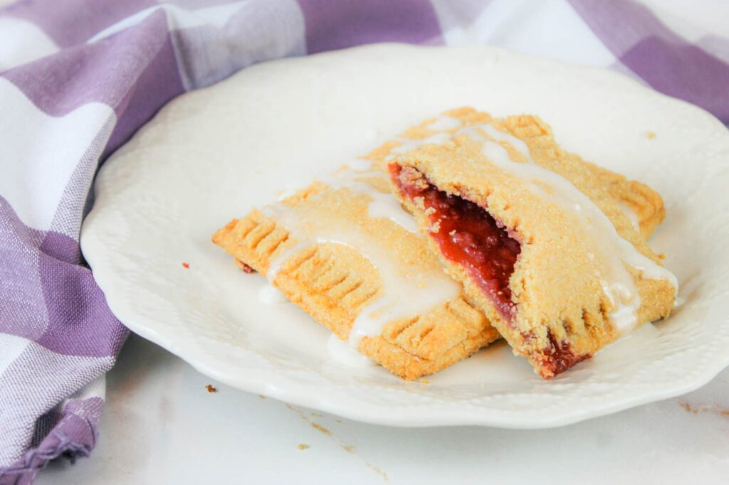 two toaster pastries sit on top of a cream colored plate next to a purple kitchen towel