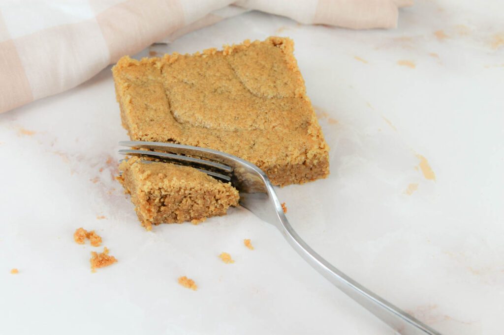 a peanut butter cookie bar is cut into pieces using a fork