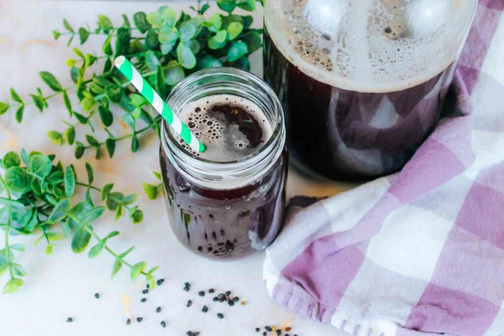 fermented elderberry soda in a mason jar with a green straw