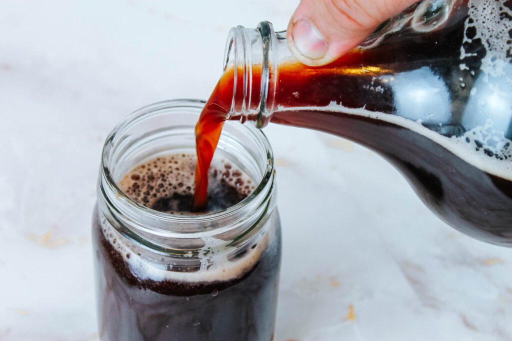 jug of soda pouring into a small cup