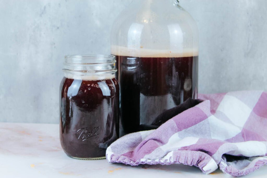 a bottle and jar sit side by side filled with elderberry soda