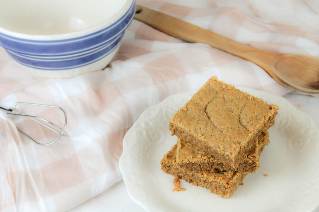 a bowl striped mixing bowl, a wooden spoon and a plate full of cookies sit on a kitchen countertop