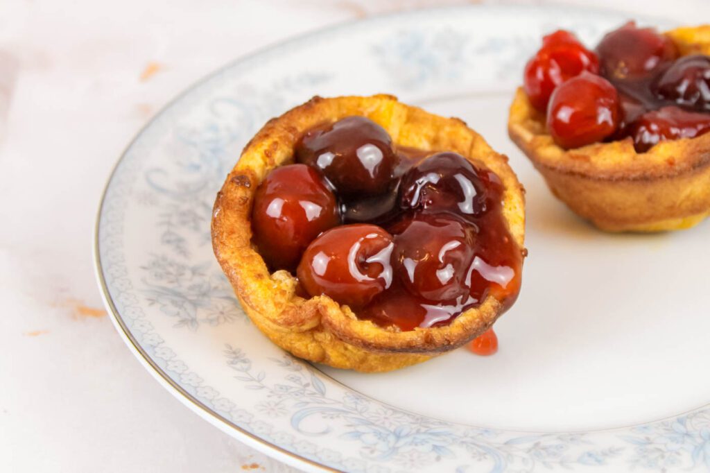 dutch baby filled with cherry sauce sitting on a blue and white floral plate