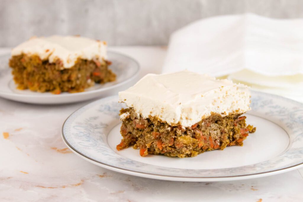 two pieces of carrot cake with fresh milled flour sitting on a set of blue floral plates
