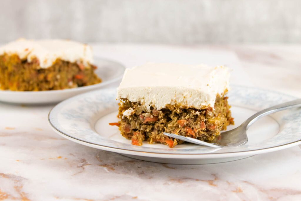 frosted slice of cake sits on a plate with a fork