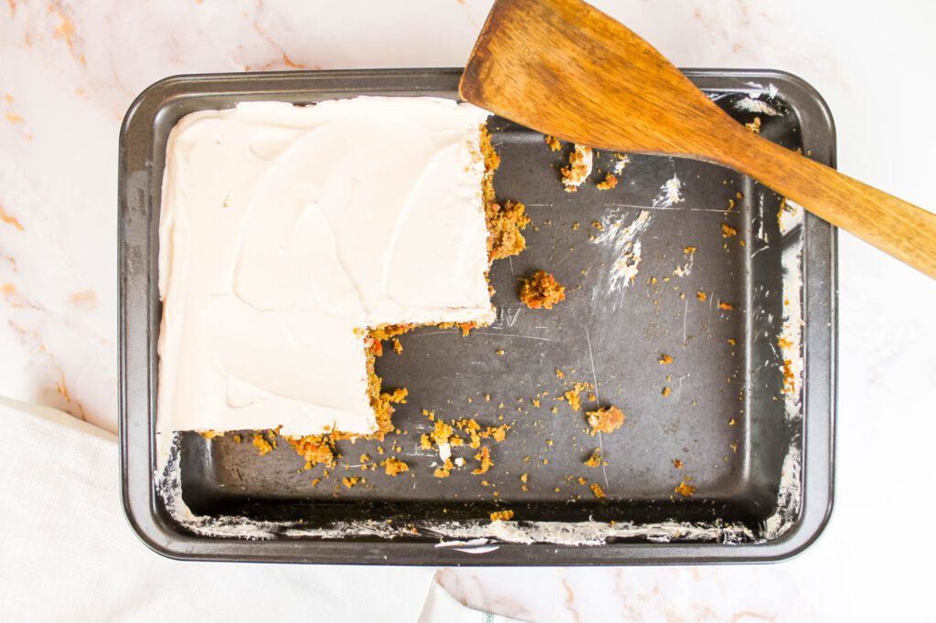 sheet cake in a metal baking pan. a wooden spatula sits in the corner of the pan.