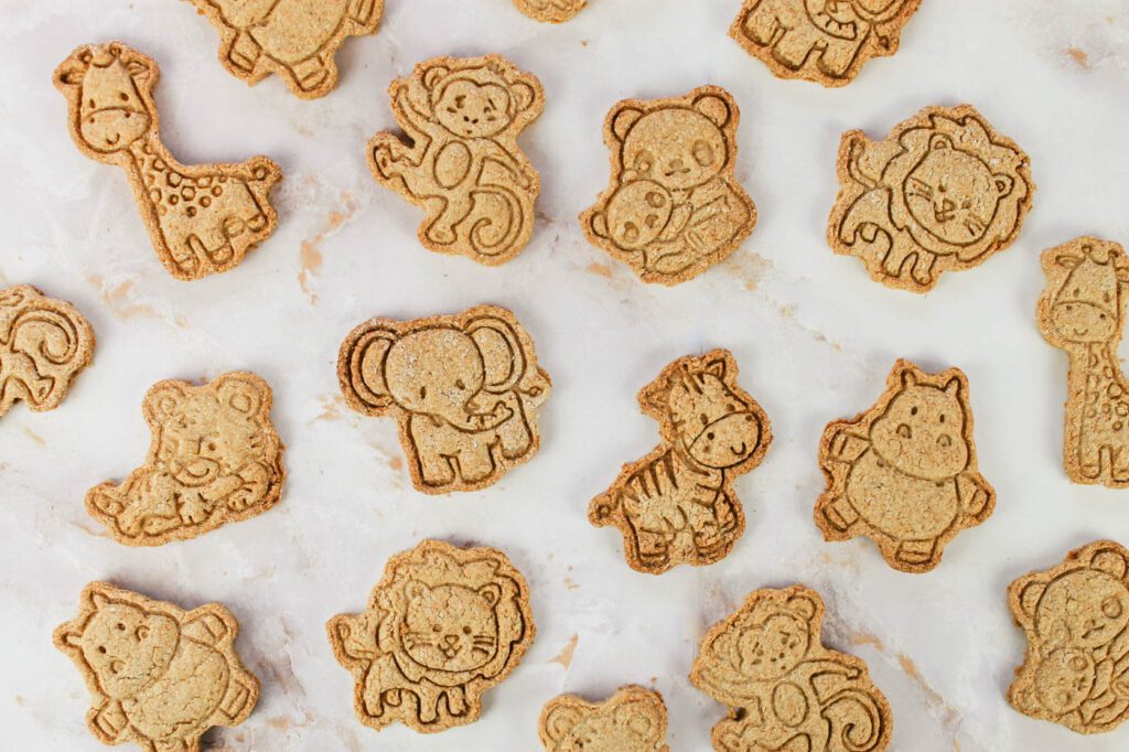 lots of animal cookies lay on top of a marble countertop in a kitchen