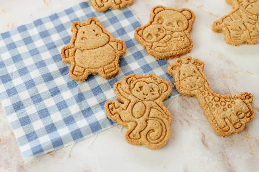 four homemade animal crackers lay on top of a blue and white plaid towel