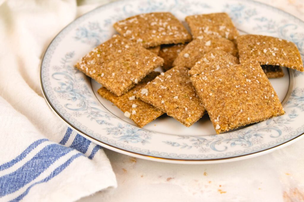 a plate of crackers sitting on a kitchen counter next to a white and blue striped towel